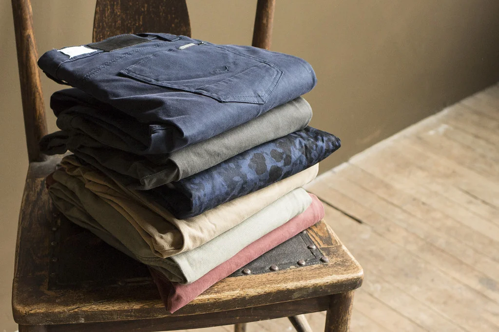 Pile de pantalons chinos slim homme plies sur une chaise en bois