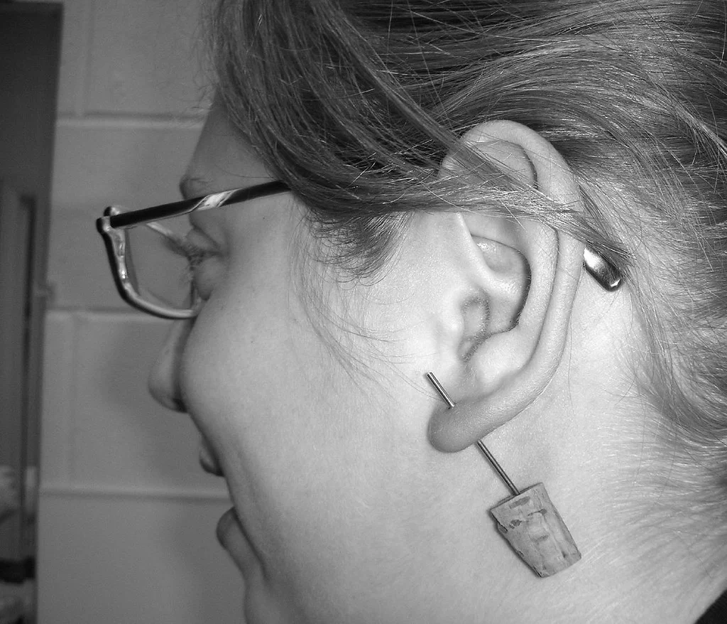 Oreille avec plusieurs piercings en titane posés sur le lobe et le cartilage